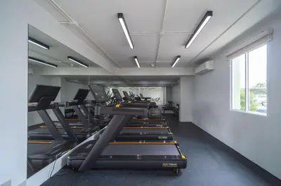 a row of treadmills in a gym with a large window at Sabai Residence @Bangyai in Nonthaburi