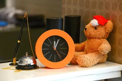 a teddy bear wearing a santa hat sitting next to a clock at iCheck inn Residences Sathorn in Bangkok