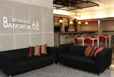 a living room with two black couches and a restaurant at Bangkok 68 in Bangkok