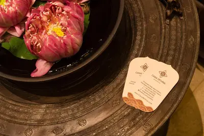 a bowl of flowers on a plate with a card at Casa Nithra Bangkok in Bangkok