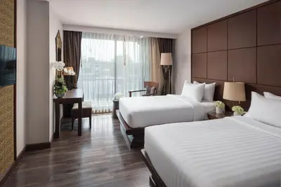 a hotel room with two beds and a desk at Casa Nithra Bangkok in Bangkok