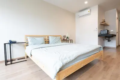 a bedroom with a large bed with white sheets at L.A. Tower Hotel in Bangkok