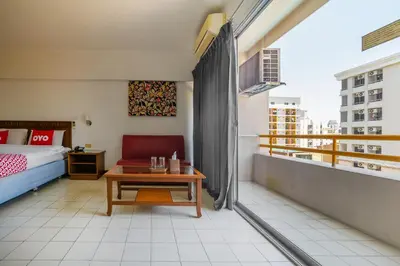 a room with a bed and a table on a balcony at L.A. Tower Hotel in Bangkok