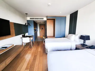 a hotel room with two beds and a desk at Montana Bangkok Hotel & Residence in Bangkok