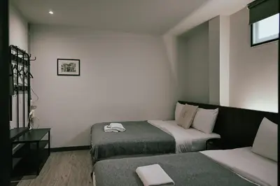 a hotel room with two beds and a couch at Tim Mansion in Bangkok