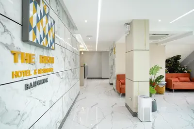 an office lobby with a red couch and a sign on the wall at The Riski Hotel at Bangphlat Station SHA in Bangkok