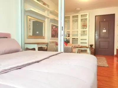 a bedroom with a white bed and a table at Rama9 Cozy Apartment in Bangkok