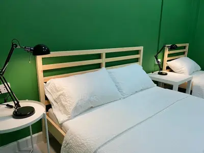 a bedroom with two beds with green walls and two lamps at Grasshopper Bed and Cafe in Pak Kret