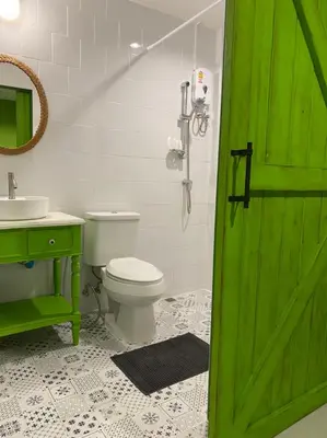 a bathroom with a green door and a toilet and sink at Grasshopper Bed and Cafe in Pak Kret