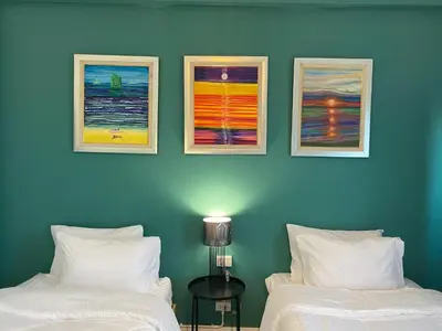 two beds in a room with three paintings on the wall at Baan Suandao Wat Arun in Bangkok