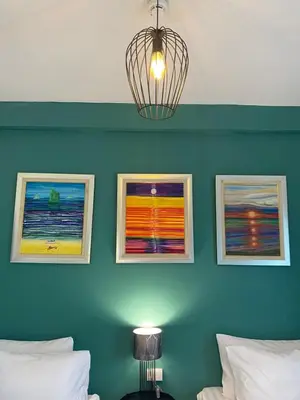 a room with three paintings on a blue wall at Baan Suandao Wat Arun in Bangkok