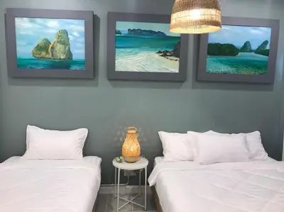 two beds in a room with three pictures on the wall at Baan Suandao Wat Arun in Bangkok
