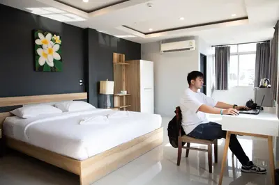 a man sitting at a desk in a bedroom at 185@Surawong Residence in Bangkok
