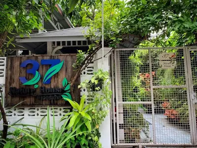 a house with a sign on the side of it with plants at 37 Nature House in Bangkok