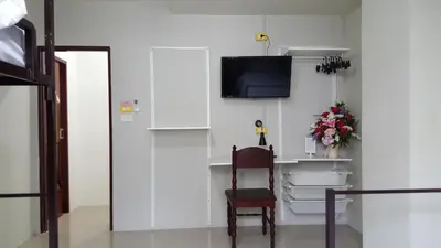 a room with a chair and a tv on a wall at Bangkok Check Inn @Chareon Krung in Bangkok