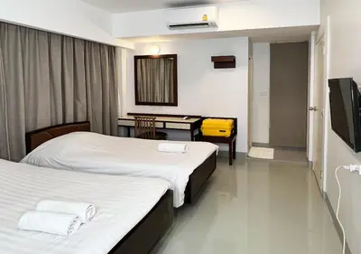 a hotel room with two beds and a desk at Niagara Hotel in Bangkok