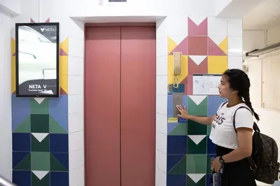 a woman standing in a room pointing at a wall at D haus Ngamwongwan Residence in Nonthaburi
