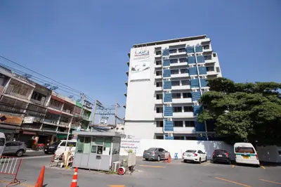a tall white building with cars parked in front of it at D haus Ngamwongwan Residence in Nonthaburi