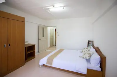 a bedroom with a white bed and a wooden cabinet at D haus Ngamwongwan Residence in Nonthaburi