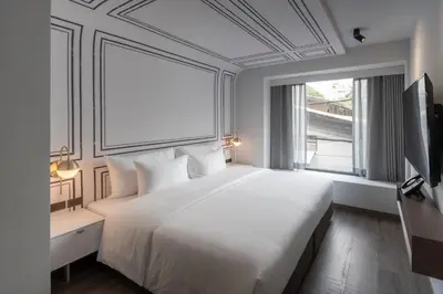a bedroom with a large white bed and a window at PASSA Hotel Bangkok in Bangkok