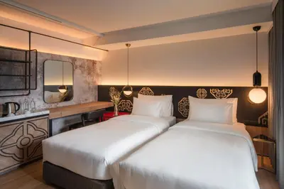 two beds in a hotel room with white sheets at PASSA Hotel Bangkok in Bangkok