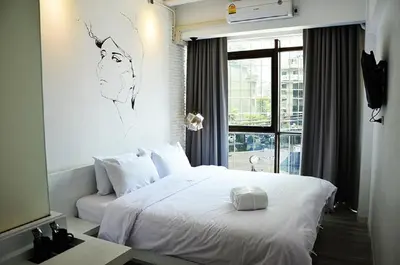 a bedroom with a white bed with a drawing on the wall at 3Howw Hostel @ Sukhumvit 21 in Bangkok