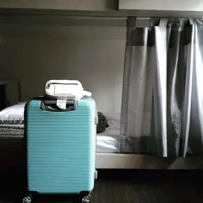 a blue suitcase sitting in front of a bed at 3Howw Hostel @ Sukhumvit 21 in Bangkok