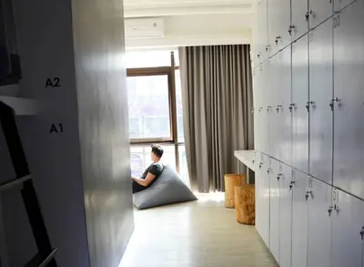 a woman sitting on the floor in a room at 3Howw Hostel @ Sukhumvit 21 in Bangkok