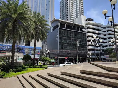 a city street with palm trees and buildings at 3Howw Hostel @ Sukhumvit 21 in Bangkok