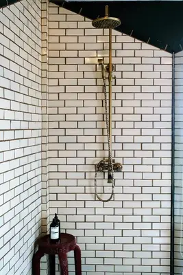 a shower in a white brick wall with a table at Ba Hao Residence in Bangkok