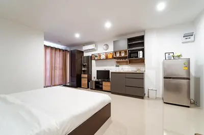 a bedroom with a bed and a kitchen with a refrigerator at My Space @ Chaosua69 in Ban Pak Khlong Khwang
