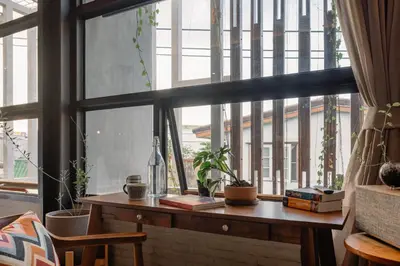 a window with a wooden table with books and plants at Tamni in Bangkok