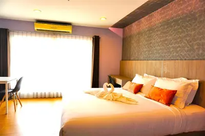 a bedroom with a large white bed with a window at Nest n Rest Hotel in Ban Bang Toei (1)