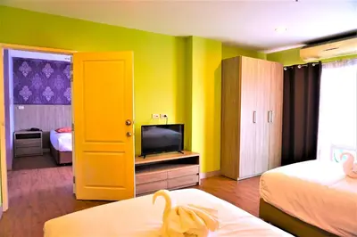 a room with a room with two beds and a television at Nest n Rest Hotel in Ban Bang Toei (1)