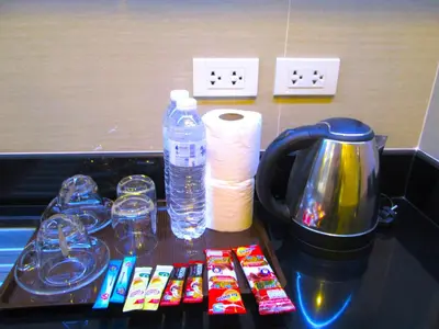 a counter with a tray with cups and water bottles at Nest n Rest Hotel in Ban Bang Toei (1)