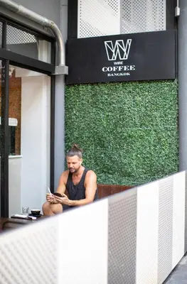 a man sitting on a window sill reading a book at WiRE BANGKOK PRAKHANONG in Amphoe Phra Khanong