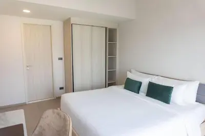 a bedroom with a large white bed with green pillows at Wyndham Garden Bangkok Sukhumvit 42 in Bangkok