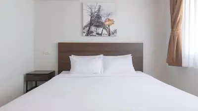 a bedroom with a white bed with a wooden headboard at Pas Cher Hotel de Bangkok in Bangkok