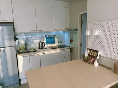 a kitchen with white cabinets and a table in it at Harmony family room in Bangkok