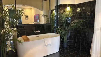 a bathroom with a bath tub and potted plants at Hotel Thomas Bangkok in Makkasan