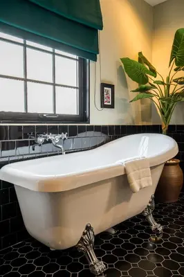 a white bath tub in a bathroom with a plant at Hotel Thomas Bangkok in Makkasan