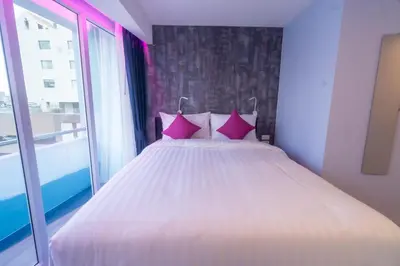 a bedroom with a bed with pink pillows and a window at Spark Hotel - MRT Queen Sirikit - SHA Extra Plus Certified in Bangkok
