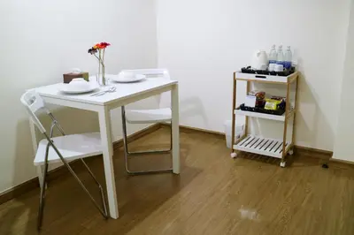 a white table and chair with a vase of flowers on it at Beerapan Hotel in Bangkok