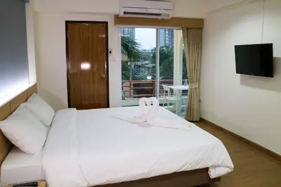 a bedroom with a white bed and a television at Beerapan Hotel in Bangkok