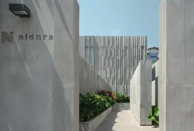 a concrete building with a sign on the side of it at Nidhra Boutique Hotel Bangkok Sukhumvit in Bangkok