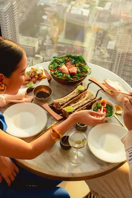 a group of people sitting at a table with food at The Standard, Bangkok Mahanakhon in Bangkok
