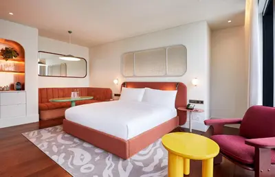 a hotel room with a bed and two chairs at The Standard, Bangkok Mahanakhon in Bangkok