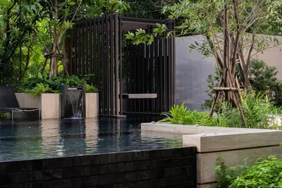 a pool of water in a garden with a fence at Gardina Asoke Hotel & Residence in Bangkok
