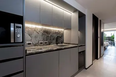 a kitchen with black and white cabinets and a microwave at Gardina Asoke Hotel & Residence in Bangkok