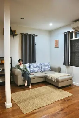 a woman sitting on a couch in a living room at Dara Three Hostel ดาราตรี in Bangkok